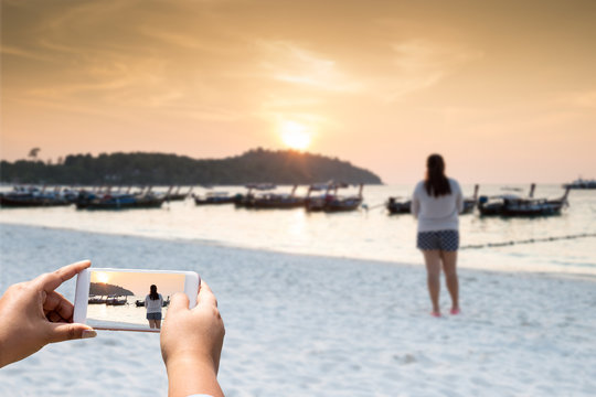 hand hold and touch screen smart phone,cellphone over blurred beautiful beach background, Koh Lipe, Thailand