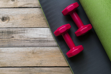 dumbbell and yoga mat on wood table