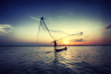silhouette fisherman and boat in river on during sunset,Thailand