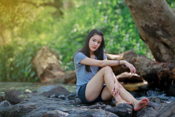 The girl is sitting at a waterfall and smiling happy