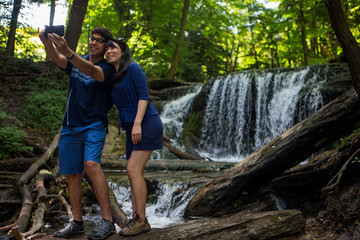 Mixed race couple take selfies at waterfall