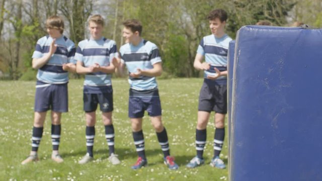  Male school rugby players cheering on female team mates at training session