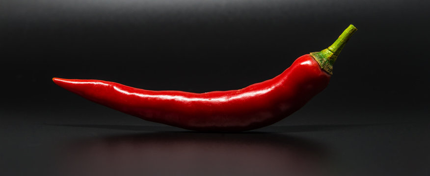 Red chili pepper isolated on black background with selective focus