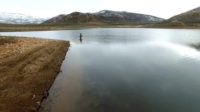 Flying over fly fisherman in lake with drone