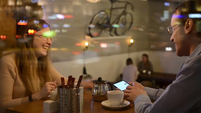 young couple drinking tea and talking in cafe