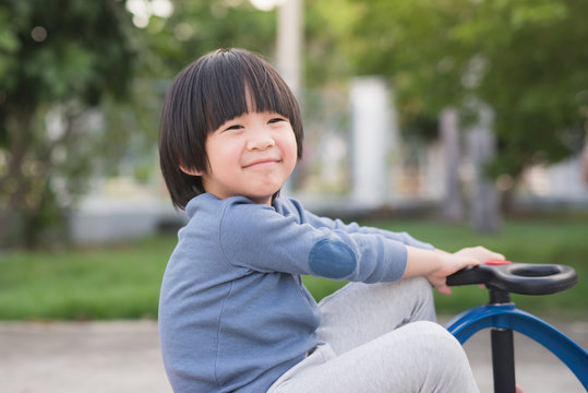 Asian child driving blue toy car outdoors