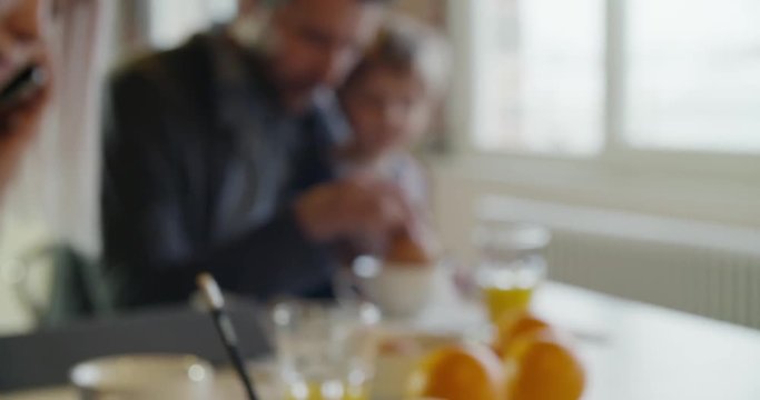 modern family little girl having breakfast with dad while mom uses smartphone and works indoor in modern industrial house. caucasian. 4k handheld slow motion video shot