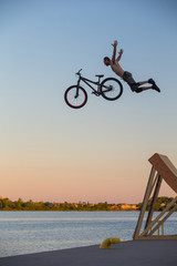 Man jumps a bicycle into the water from a pier