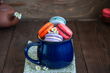 Mix of colored macarons in a blue jar on a wooden background