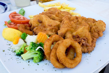 Vienna schnitzel with onion rings and quickly boiled vegetables served at the restaurant in Sombor, Serbia
