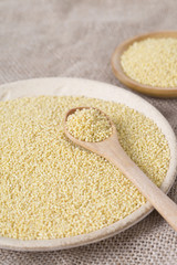 Yellow millet seeds in a wooden bowl on the table