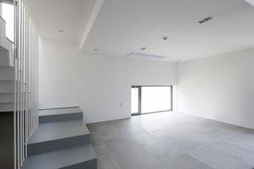 white empty living room with stair, wood floor, window, pendant lighting.