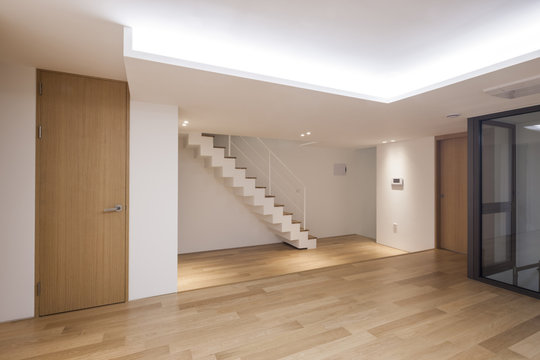 white empty living room with stair, wood floor, window, pendant lighting.