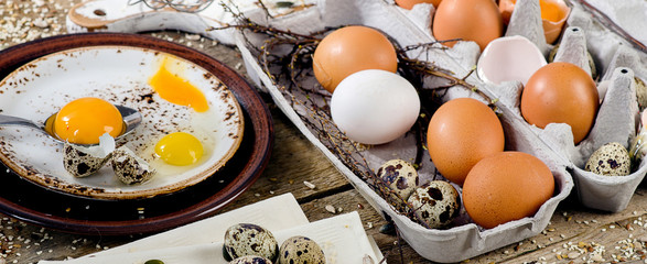 Chicken and quail eggs on a rustic wooden background