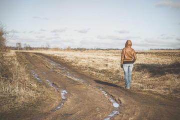 Girl goes along muddy country road. Early spring time. Vintage style.