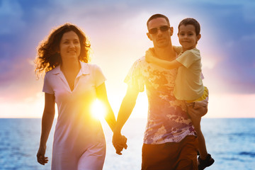 Happy family walking at sunset beach