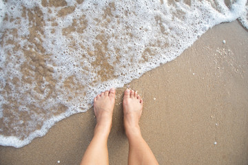 foot of human on sand and soft wave on the sea.
