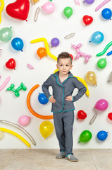 Fototapeta premium boy on a white background with colorful balloons. boy in pajamas on a white background with balloons in the shape of heart