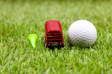 golf ball with London double decker bus on green course.