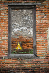 The old Buddha statue, look through the window in the ancient country of Thailand.