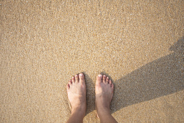 foot of human on sand and soft wave on the sea.