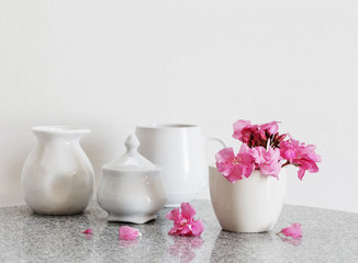 Clean dishes and flowers on white background