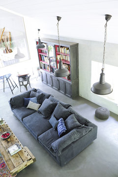 Living room with blue sofa, iron suspensions and concrete floor for an industrial style