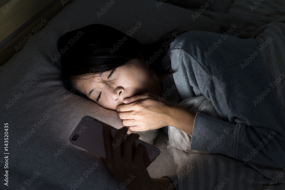 Poster woman feeling tired and using mobile phone on bed