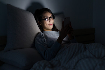 Obraz premium Woman watching on mobile phone at night