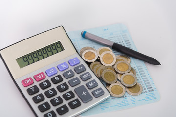 Increasing columns of coins, piles of coins arranged as a graph and calculator with pen on white background