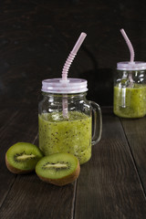 Fresh and healthy green Juice smoothie with kiwi  in glass jar. On dark background