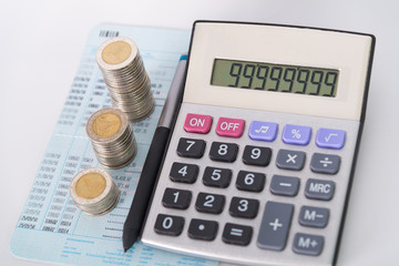 Increasing columns of coins, piles of coins arranged as a graph and calculator with pen on white background