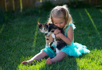 Little girl snuggles with a kitten in the backyard
