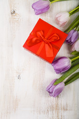 Bouquet of tulips and a gift on a wooden background.