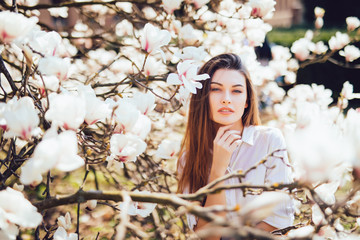 Fototapeta premium Portrait of beautiful woman with magnolia flowers. Spring time