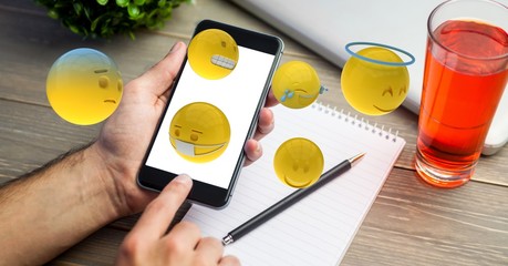 hand using smart phone while emojis flying over table