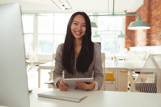 Portrait Of Female Executive Holding Digital Tablet At Desk