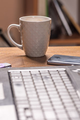 Cup of coffee on the table with blurred lap top