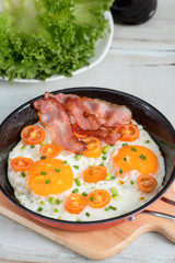 Pan of fried eggs, bacon and tomato.