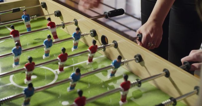 group of friends playing table football. indoor in modern industrial house. caucasian. 4k handheld slow motion detail video shot