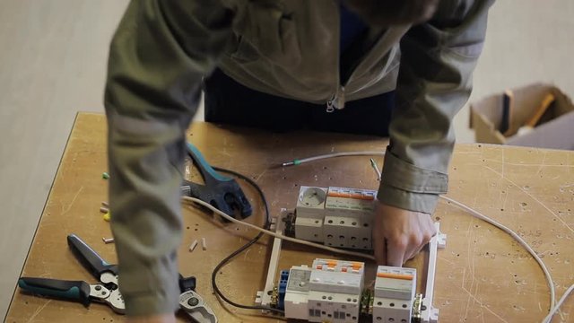 Professional electric inserts connecting wires to automatic fuses. Different settings for protection against short circuit, overheating in switchboard on background of wooden table. Equipment with
