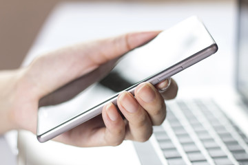 Hand holding mobile smartphone with blank screen.