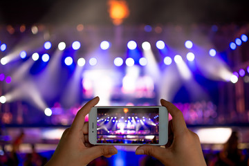 Image of hands using camera phone to take pictures and videos at live concert.