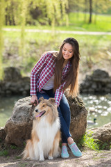 young beautiful woman with long hair walking with collie dog. Outdoors in the park.