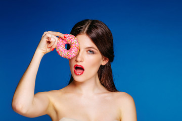 Young girl brunette model on the background of bright blue walls. Beautiful girl love to posing with a balloon and a doughnut.