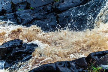 Yellow-brown splashes of water from the waterfall of Akhvenkoski in Karelia