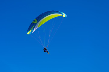 The paraglider flies in the blue sky