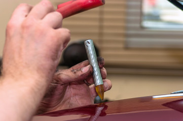 Hands of car mechanic in auto paintless dent repair service.