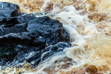 Yellow-brown splashes of water from the waterfall of Akhvenkoski in Karelia