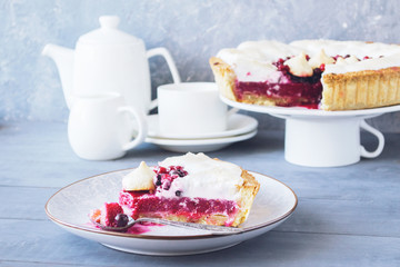 A piece of berry pie with a meringue served on a white dish